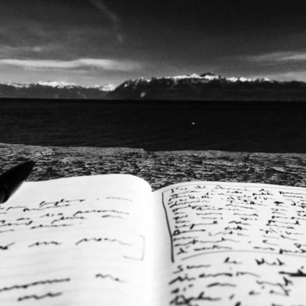 Papier et stylo sur un rocher avec vue sur lac et montagnes enneigées, ambiance inspirante et poétique.